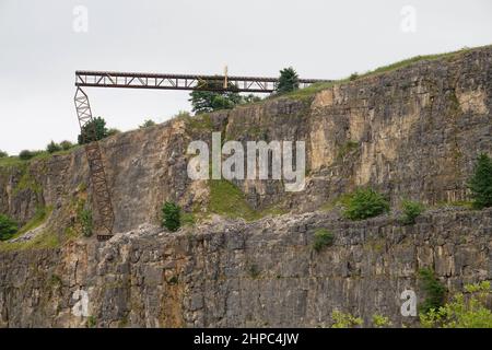 Eine gefälschte Eisenbahnbrücke, die über einem stillgelegten Steinbruch im Peak District, Großbritannien, für einen Stunt mit einem Zugunfall für den Film Mission Impossible 7 gebaut wurde. Stockfoto