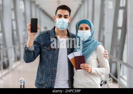 Islamische Ehepartner Tragen Medizinische Gesichtsmasken Am Flughafen Und Demonstrieren Unbeschriftete Smartphones Stockfoto