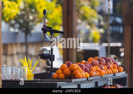 Nahaufnahme eines manuellen Entsafters aus Metall und einer Menge frischer Orangen auf dem Ladentisch Stockfoto