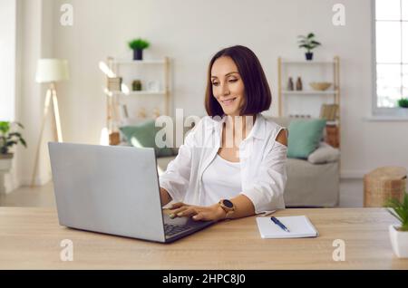 Eine schöne lächelnde Geschäftsfrau, die mit einem Laptop in ihrem Home Office arbeitet. Stockfoto
