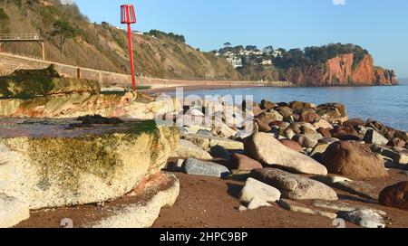 Felsen am Strand neben dem baufälligen Wellenbrecher am Sprey Point Teignmouth, mit Blick auf Hole Head bei Ebbe. Stockfoto