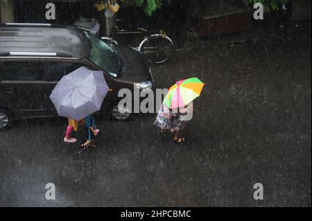 Mumbai; Maharashtra; Indien- Asien, Juni, 2019 : verschwommenes Bild, Luftaufnahme, Kinder gehen mit einem Regenschirm über den Kopf, wenn es stark regnet Stockfoto