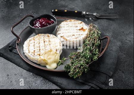 Gebackener Camembert-Käse auf einem Stahlblech mit Cranberry-Sauce und Thymian. Schwarzer Hintergrund. Draufsicht Stockfoto