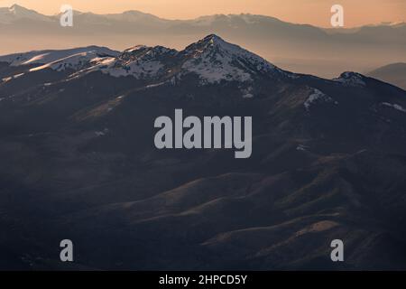 Die untergehende Sonne fällt auf die schneebedeckten Berggipfel Stockfoto