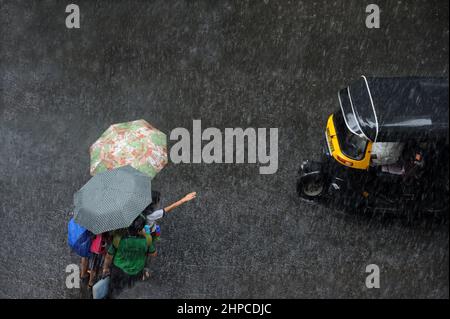 Mumbai; Maharashtra; Indien- Asien, Juni, 2019 : verschwommenes Bild, Luftaufnahme, Kinder gehen und warten auf Riksha, der einen Regenschirm über seinen Kopf hält Stockfoto