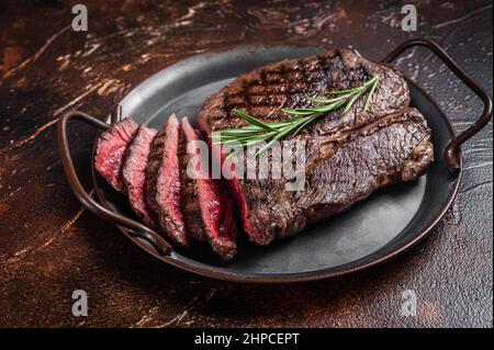 Gegrilltes Medium Rare Top-Rindersteak oder Rumpsteak auf einem Stahltablett. Dunkler Hintergrund. Draufsicht Stockfoto