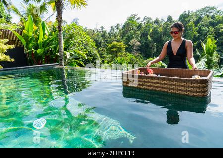 Frau genießt das schwimmende Frühstück im Luxusresort in Bali Stockfoto