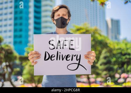 Mann in medizinischer Maske verhindert Coronavirus-Krankheit hält ein Poster Safe Delivery Hand geschriebener Text - Schriftzug isoliert auf weiß. Coronovirus COVID 19 Stockfoto