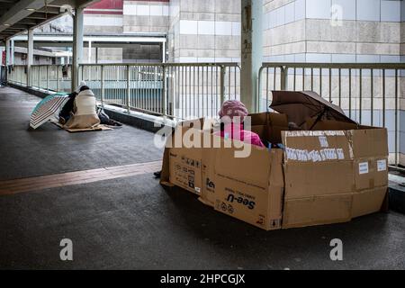 Hongkong, Hongkong. 20th. Februar 2022. Ausländische Hausangestellte versammeln sich in Admiralty zur Erholung und Erholung an ihrem einen freien Tag pro Woche. Angesichts der steigenden Anzahl von COVID-19-Fällen und einer Warnung des Chefs vor der Einhaltung der sozialen Distanzierungsregeln waren viele ausländische Arbeitnehmer vorsichtig, ihre Gruppen auf zwei zu beschränken, da sie sich vor Kälte und Regen schützten. Kredit: SOPA Images Limited/Alamy Live Nachrichten Stockfoto