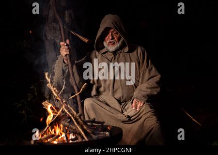 Mönch im Mittelalter singt am Lagerfeuer Stockfoto