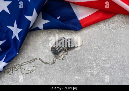 Army Dog Tag-Marke mit 9mm Kugeln und Pistole liegen auf gefalteter US-Flagge Stockfoto