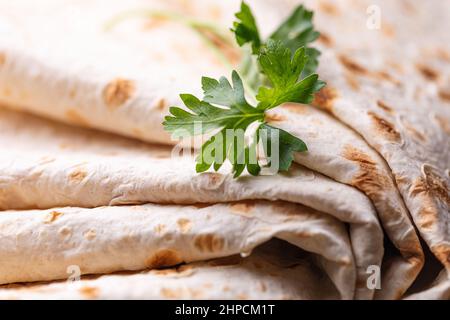 Lavasch rollte auf einem hölzernen Hintergrund, dünnes traditionelles orientalisches Brot, armenisches Fladenbrot-Makro, Nahaufnahme Stockfoto