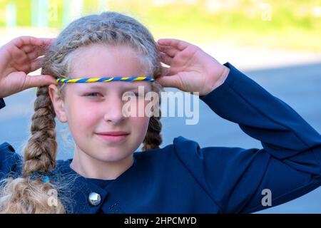 Schulmädchen hält Hand auf Herz! patriot, stolzes Mädchen, das Konzept des Stolzes. Das Konzept des Stolzes als alles andere, Patriotismus . Nationale Farben der Ukraine, Stockfoto