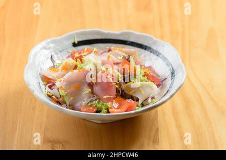 japanische Gerichte mit frischen Kaisen Salatlachs-Sashimi-Scheiben in einer Schüssel mit rohem Fisch auf Holzhintergrund von oben Stockfoto