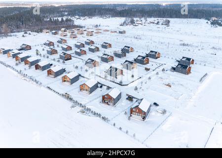 Draufsicht auf das Winterdorf mit schneebedeckten Häusern und Straßen Stockfoto