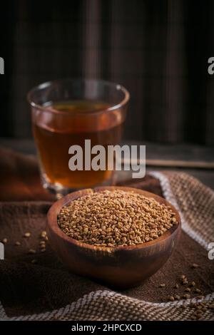 Schale mit Bockshornkleesamen und ägyptischem Bockshornkleesee oder Methi Dana Drink auf dunklem Holzhintergrund Stockfoto