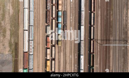 Luftaufnahme von bunten Güterzügen mit Waren auf dem Bahnhof. Stockfoto