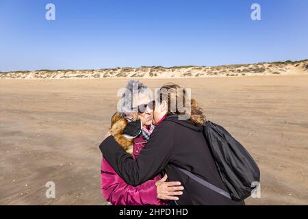 Eine reife Frau küsst und umarmt ihre ältere Mutter am Strand Stockfoto