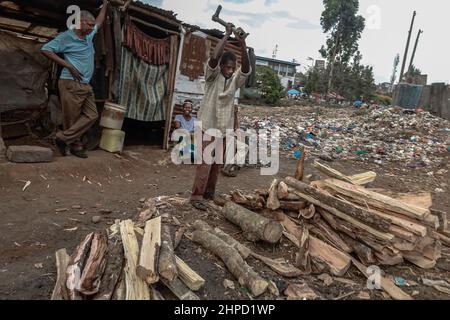 Ein Mann schneidet in den Slums von Kibera in Nairobi Brennholz auf den Straßen. Im Kibera Slum, dem berüchtigten Zuhause, wo das Leben immer schwierig und klägig zu sein scheint Stockfoto