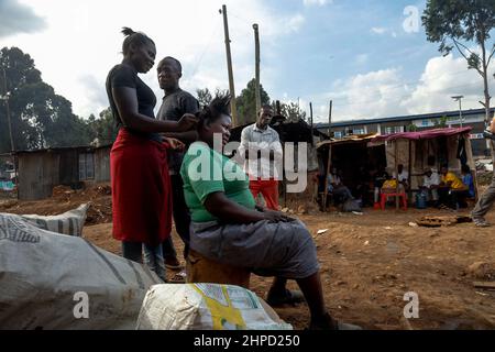 Bewohner tauschen sich außerhalb ihrer Häuser in den Slums von Kibera in Nairobi aus. Im Kibera Slum, dem berüchtigten Zuhause, in dem das Leben immer wie di erscheint Stockfoto