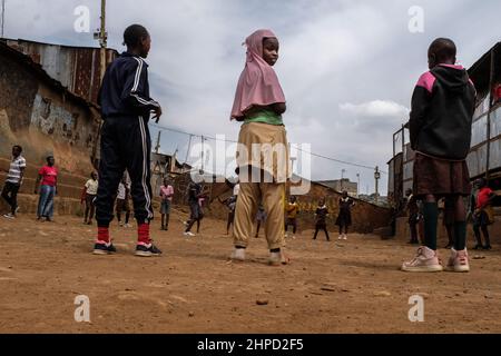 Die Schüler spielen auf einem lokalen Spielplatz in den Slums von Kibera in Nairobi. Im Kibera Slum, dem berüchtigten Zuhause, in dem das Leben immer schwierig und challe zu sein scheint Stockfoto