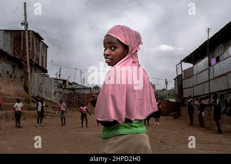 KENIA, Nairobi, Kibera Slum, muslimisches Mädchen, das während der Schulferien auf der Straße spielt. Im Kibera Slum, der berüchtigten Heimat, in der das Leben immer scheint Stockfoto