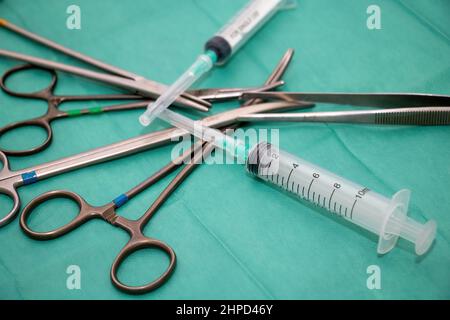 Sterilisiertes Operationsinstrument auf grünem Stoffhintergrund. Chirurg Arzt Edelstahlwerkzeug, Pinzettenzange, Nadelhalter oder Treiber, Zange, Schere und Stockfoto