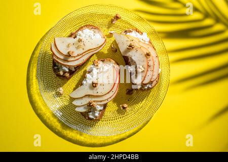 Bruschetta mit Birne, Ziegenkäse-Aufstrich, Nüssen und Honig Stockfoto