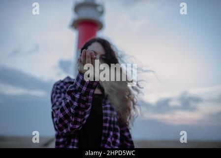 Frau, die eine Handvoll Sand vor ihr Gesicht fallt. Zeit und verloren Stockfoto