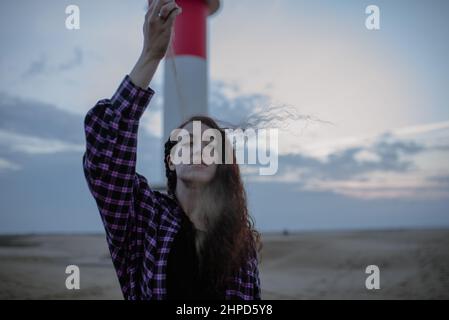 Frau, die eine Handvoll Sand vor ihr Gesicht fallt. Zeit und verloren Stockfoto