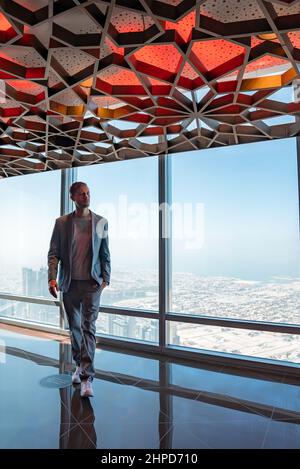 Junger Mann, der Dubai vom Wolkenkratzer Burj Khalifa aus erkundet. Stockfoto