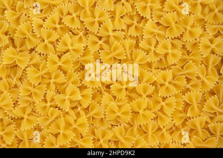 Traditionelle italienische Farfalle-Pasta als Hintergrund, Rohkost-Textur aus der Nähe, ungekochte getrocknete hausgemachte Farfalle Stockfoto
