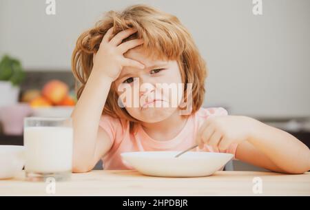 Unfokussierter kleiner Junge, der zum Mittagessen Suppe hat. Unglücklich kaukasischen Kind sitzen am Tisch in der Küche zu Hause haben keinen Appetit. Verärgert kleines Kind weigert sich zu essen Stockfoto