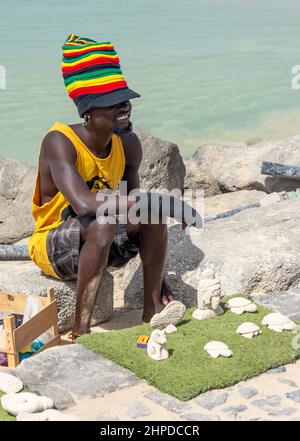 Mann, der geschnitzte Sandfiguren auf der Fischeranlegestelle Pontao Santa Maria, Praia Santa Maria, Santa Maria, Sal, República de Cabo (Kap Verde) verkauft Stockfoto