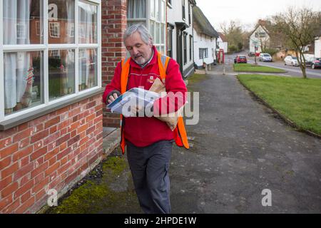 Postbote, der Briefe in einem Suffolk-Dorf, Großbritannien, ausliefert. Stockfoto