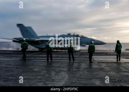 PHILIPPINISCHES MEER (Feb 19, 2022) Matrosen beobachten einen EA-18G Growler, der den 'Wizards' des Electronic Attack Squadron (VAQ) 133 zugewiesen wurde, der vom Flugdeck des Nimitz-Klasse-Flugzeugträgers USS Abraham Lincoln (CVN 72) gestartet wird. Die Abraham Lincoln Strike Group befindet sich im geplanten Einsatzgebiet der US-Flotte für 7th, um die Interoperabilität durch Allianzen und Partnerschaften zu verbessern und gleichzeitig als reaktionsfähige Truppe zur Unterstützung einer freien und offenen Region im Indo-Pazifik-Raum zu dienen. (USA Navy Foto von Mass Communication Specialist 3rd Klasse Michael Singley) Stockfoto