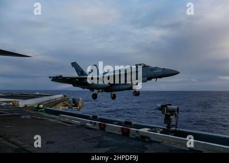 PHILIPPINISCHES MEER (Feb 19, 2022) eine F/A-18E Super Hornet, die den 'Tophoattern' des Strike Fighter Squadron (VFA) 14 zugewiesen wurde, startet vom Flugdeck des Nimitz-Klasse-Flugzeugträgers USS Abraham Lincoln (CVN 72). Die Abraham Lincoln Strike Group befindet sich im geplanten Einsatzgebiet der US-Flotte für 7th, um die Interoperabilität durch Allianzen und Partnerschaften zu verbessern und gleichzeitig als reaktionsfähige Truppe zur Unterstützung einer freien und offenen Region im Indo-Pazifik-Raum zu dienen. (USA Navy Foto von Mass Communication Specialist 3rd Klasse Michael Singley) Stockfoto