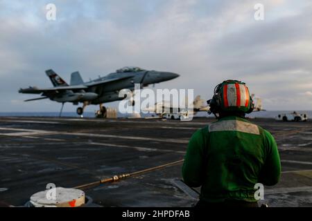 PHILIPPINISCHES MEER (Feb 19, 2022) Aviation Boatswain's Mate (Equipment) 2nd Klasse Christopher Hope aus Chicago beobachtet den Flugbetrieb auf dem Flugdeck des Flugzeugträgers USS Abraham Lincoln (CVN 72) der Nimitz-Klasse. Die Abraham Lincoln Strike Group befindet sich im geplanten Einsatzgebiet der US-Flotte für 7th, um die Interoperabilität durch Allianzen und Partnerschaften zu verbessern und gleichzeitig als reaktionsfähige Truppe zur Unterstützung einer freien und offenen Region im Indo-Pazifik-Raum zu dienen. (USA Navy Foto von Mass Communication Specialist 3rd Klasse Michael Singley) Stockfoto