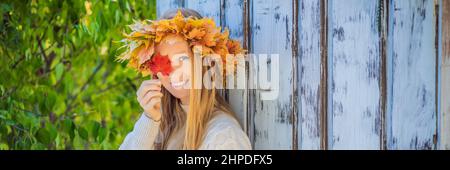 Outdoor Lifestyle Nahaufnahme Porträt von charmanten blonde junge Frau trägt einen Kranz aus Herbstblättern. In modischem Strickpullover. Kranz von Stockfoto