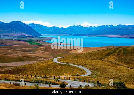 Die kurvenreiche Straße vom Gipfel des Mt John's Observatory führt zum Lake Tekapo und den schneebedeckten südlichen Alpen Stockfoto