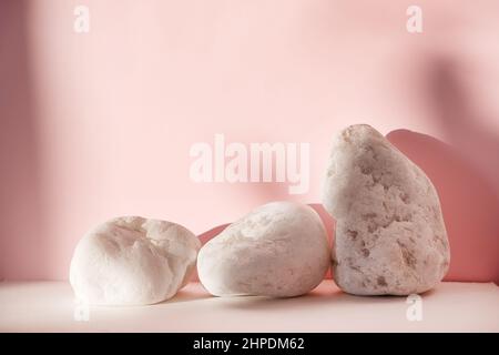 Weiße Steine auf rosa pastellfarbenem Hintergrund. Abstrakter Hintergrund, imitierte minimale Szenengeometrie Form Podium für kosmetische Produktanzeige. Bühnenpodest Stockfoto