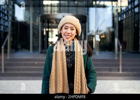 Junge asiatische Geschäftsfrau suchen Kamera lächelnd. Fröhliche chinesische Dame lächelt für die Erfolge der Arbeit. Stockfoto