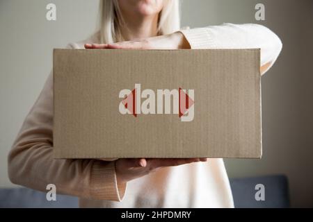 Frau, die ein Paket in den Händen hält, ein Geschenk zu Hause, erhielt der Kunde eine Bestellung im Online-Shop, Lieferservice Stockfoto