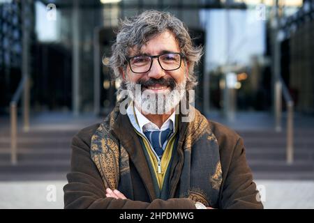 Kaukasischer Geschäftsmann mittleren Alters, der lächelnd auf die Kamera schaut. Graues Haar 50 Jahre alter fröhlicher Mann glücklich über die Erfolge der Arbeit. Stockfoto