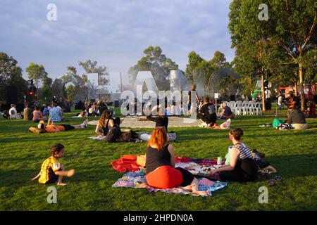 Open-Air-Konzert-Besucher picknicken auf einem Rasen im späten Nachmittagslicht Stockfoto