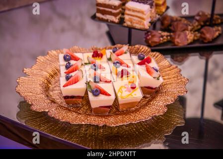 Schokoladenkuchen mit Zuckerguss und Streuseln auf einem braunen Teller Stockfoto