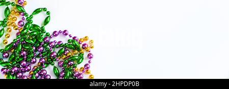 Mardi Gras Hintergrund. Bunte Perlen auf weißem Hintergrund. Fat Tuesday-Symbol. Festliche Dekorationen in Gold, Grün und Lila für Traditiona Stockfoto