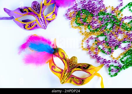 Zwei Karnevalsmasken mit Federn und bunten Perlen auf weißem Hintergrund. Symbol „Mardi Gras“ oder „Fat Tuesday“. Grußkarte für traditionelle holi Stockfoto