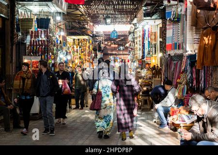 Touristen und Einheimische navigieren durch die belebten Fußgängerwege in der Medina, Marrakesch und Marokko Stockfoto