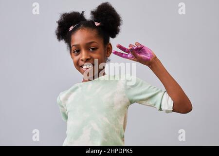 Minimal Taille up Porträt von glücklichen afroamerikanischen Mädchen mit Farbe auf den Händen posiert vor weißem Hintergrund im Studio Stockfoto